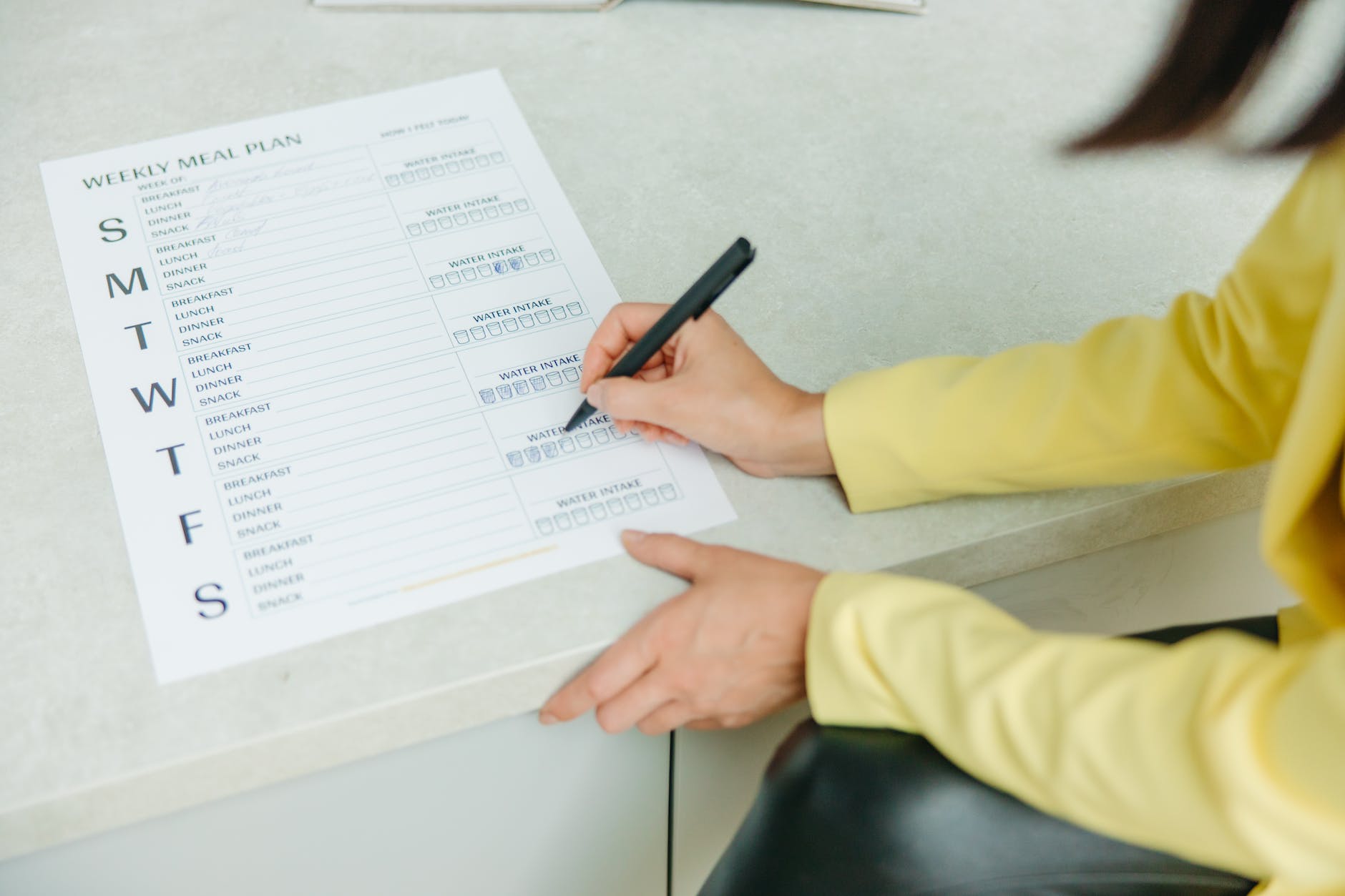 a person holding a black pen writing on white paper
